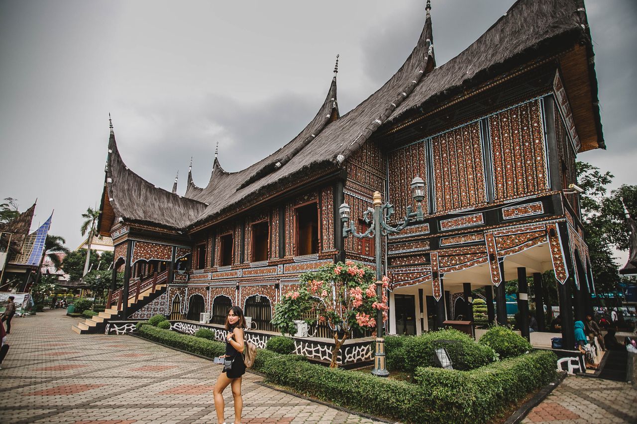 Beautiful traditional Indonesian building with detailed architecture and a person walking nearby.